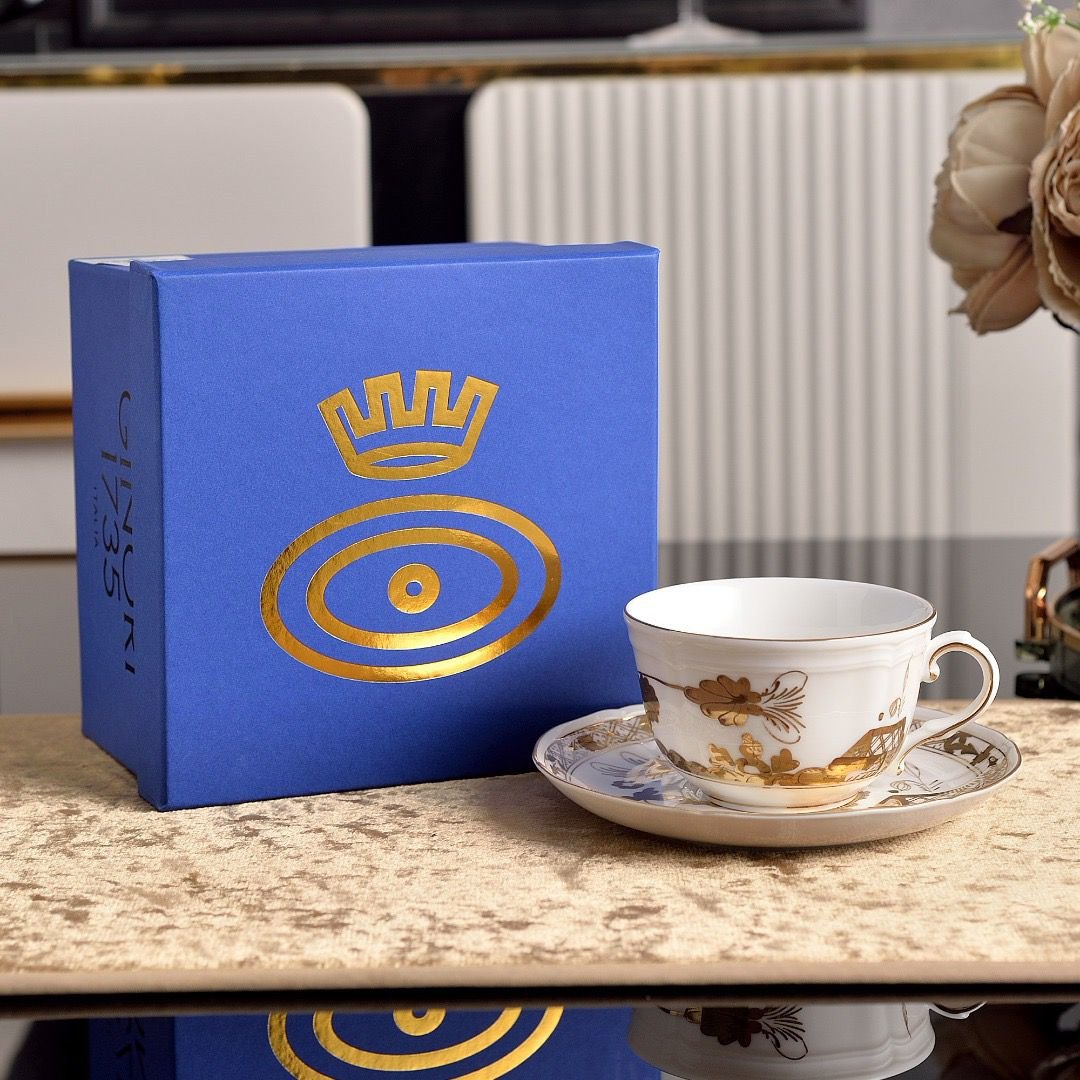 A coffee cup and saucer from Ginori 1735 Oriente Italiano Aurum, made of white porcelain and decorated with floral motifs painted in gold.